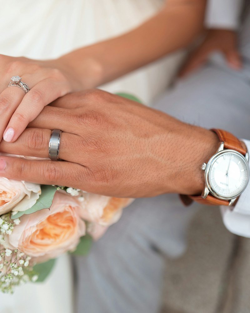 Two hands resting together, wedding rings on show